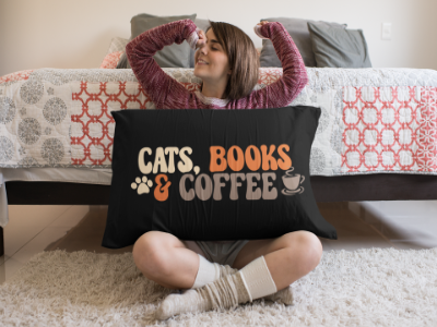 woman sitting on the floor with a black pillow saying "cats, books & coffee"